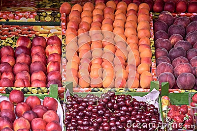 Street market: colorful juicy fruits. Counter with trays filled with ripe fruits of cherries, peaches and strawberries. Healthy Stock Photo
