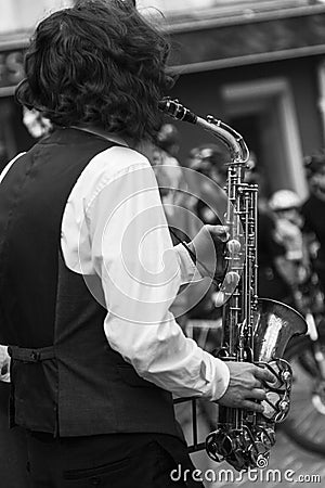 Street musician`s hands playing saxophone in an urban environment. Black and white picture Editorial Stock Photo