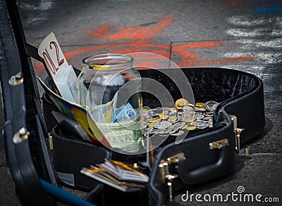 Street Musicians money in different currencies in the guitar case. Stock Photo