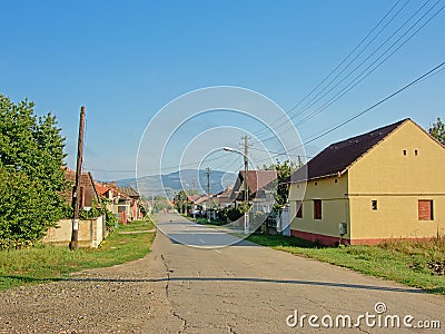 Street in the old Romanian village Aurel Vlaicu with transylvanian mountains in the background Editorial Stock Photo