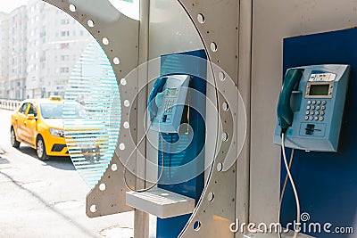 Street payphone with yellow taxi in the background. Travel concept, passenger transportation, communication. City Stock Photo