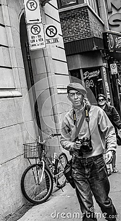 Street photographer seen with camera gear around his neck in a side street in Montreal. Editorial Stock Photo