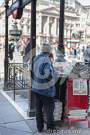 Street Photography: Elderly Newspaper Salesman with a hat in Londonâ€™s Street Editorial Stock Photo