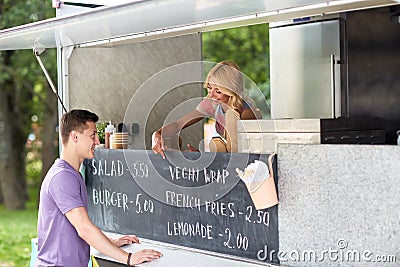 Saleswoman at food truck serving male customer Stock Photo