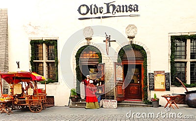 Street scene in old Tallinn, Estonia 15,11,2019 girl in medieval red dresses selling fried almonds for tourist in an old tradi Editorial Stock Photo