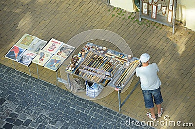 Souvenir seller standing near trays with handmade souvenirs and old soviet posters Editorial Stock Photo