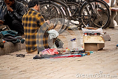 street side cobbler sitting on road and mending shoes in the winter months in sector 17 chandigarh during morning Editorial Stock Photo