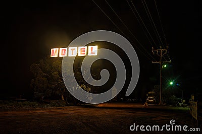 Neon sign of a cheap motel, a large truck looming in the background. Stock Photo