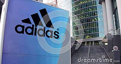 Street signage board with Adidas inscription and logo. Modern office center skyscraper and stairs background. Editorial Editorial Stock Photo