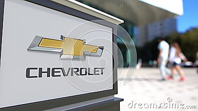 Street signage board with Chevrolet logo. Blurred office center and walking people background. Editorial 3D rendering Editorial Stock Photo