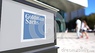 Street signage board with The Goldman Sachs Group, Inc. logo. Blurred office center and walking people background Editorial Stock Photo