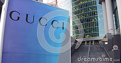 Street signage board with Gucci logo. Modern office center skyscraper and stairs background. Editorial 3D rendering Editorial Stock Photo