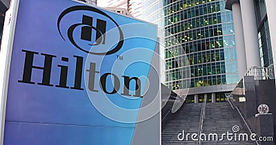 Street signage board with Hilton Hotels Resorts logo. Modern office center skyscraper and stairs background. Editorial Editorial Stock Photo