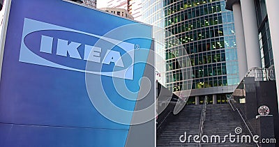 Street signage board with Ikea logo. Modern office center skyscraper and stairs background. Editorial 3D rendering Editorial Stock Photo