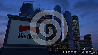 Street signage board with Marlboro logo in the evening. Blurred business district skyscrapers background. Editorial 3D Editorial Stock Photo