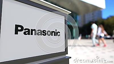 Street signage board with Panasonic Corporation logo. Blurred office center and walking people background. Editorial 3D Editorial Stock Photo