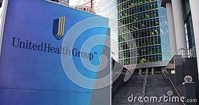 Street signage board with UnitedHealth Group logo. Modern office center skyscraper and stairs background. Editorial 3D Editorial Stock Photo