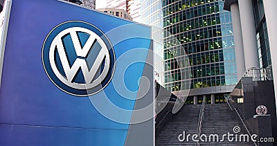 Street signage board with Volkswagen logo. Modern office center skyscraper and stairs background. Editorial 3D rendering Editorial Stock Photo