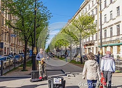 A street singer performing guitar and singing with people passing by at the corner in the Nevsky Avenue, St. Petersburg Editorial Stock Photo