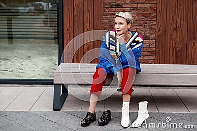 Street style. Adult, beautiful woman sitting and thinking, choosing which shoes to wear Stock Photo