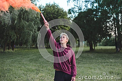 Street style man in hoodie hold hand flare with red smoke grenade bomb. Stock Photo