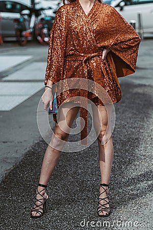Street style, woman wearing orange belted short dress and black shiny leather laces heels shoes Editorial Stock Photo