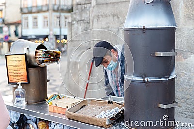 Street vendor of hot chestnuts cooked over charcoal in Porto, Portugal Editorial Stock Photo