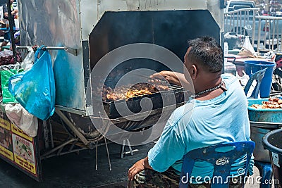 Street vendor prepares traditional Thai style grilled meat stick Editorial Stock Photo