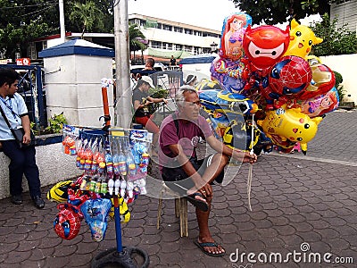 A street vendor sells bubble makers and cartoon character balloons at a park. Editorial Stock Photo