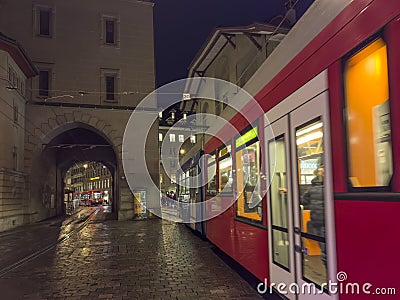 Street view of Bern. Blue red tram goes on the street near walking people in the night time. Editorial Stock Photo