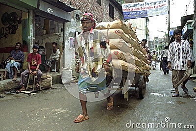 Street view of Dhaka with porter lugging cement Editorial Stock Photo