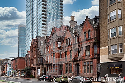 Street view of an old, red brick apartment building with modern office skyscraper behind Editorial Stock Photo