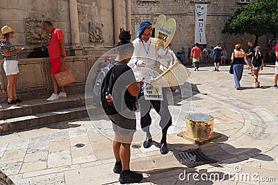 On the streets of Dubrovnik Croatia, happy vacationers walk and buy souvenirs from the seller in the national festive Editorial Stock Photo