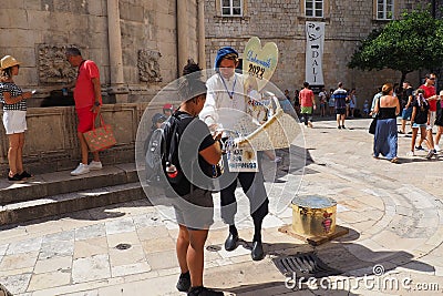 On the streets of Dubrovnik Croatia, happy vacationers walk and buy souvenirs from the seller in the national festive Editorial Stock Photo