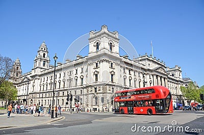 Streets of London, UK with the Government Offices building, people walking and a red bus. Editorial Stock Photo