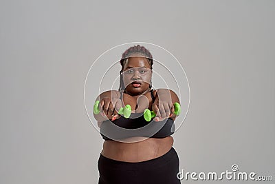 Strength and Experience. Plump, plus size african american woman in sportswear reaching arms forward, holding green Stock Photo