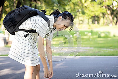 Stress asian child girl carrying heavy school bag or backpack, female teenage feeling pain on back, full of books on her back, Stock Photo