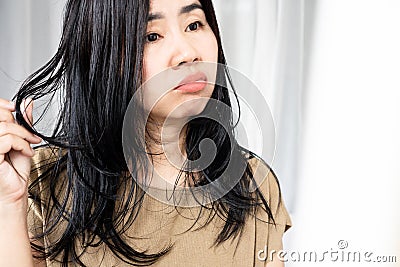 Asian woman have problems with oily hair and thinning hair looking at the mirro Stock Photo