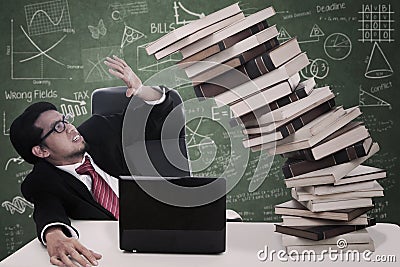 Stress businessman with falling books at class Stock Photo