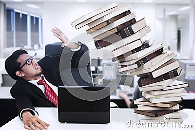 Stress businessman and falling books at office Stock Photo