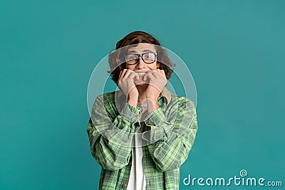 Stress control concept. Frightened young man biting fingernails in panic on torquoise background Stock Photo