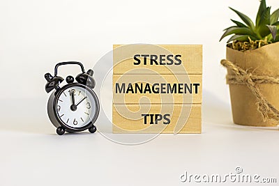 Stress management tips symbol. Wooden blocks with words `Stress management tips`. Beautiful white background. Black alarm clock. Stock Photo