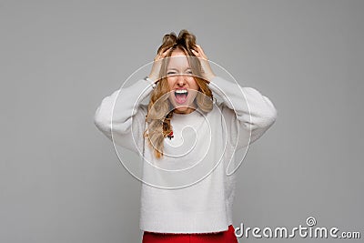 Stress. Woman stressed is going crazy pulling her hair in frustration and shouting from regret. Young emotional woman, wears white Stock Photo