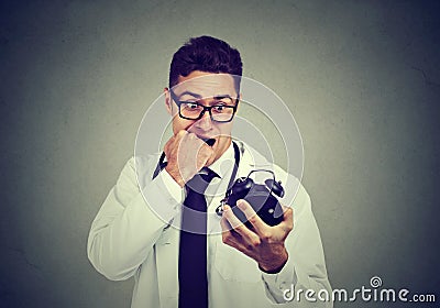 Stressed anxious doctor, health care professional holding alarm clock pressured by time Stock Photo