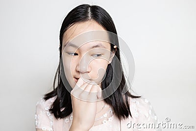 Stressed asian lady girl bites finger nails,thinking about something,anxious problems,scared,anxious with hand on mouth biting her Stock Photo