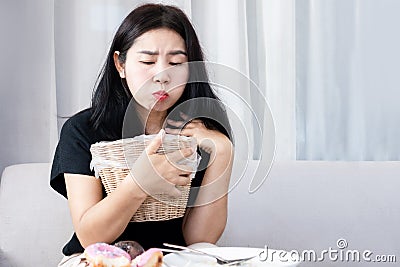 Asian woman holding bin in hand tries to vomit and diet after eating food, Bulimia nervosa, anorexia nervosa concept Stock Photo