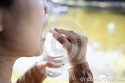 Stressed asian woman holding white pill and glass of water in hand,tired female people suffer from depression taking medicine Stock Photo