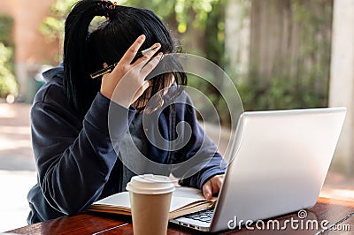 A stressed Asian woman is working on her project on her laptop, facing issues with her work Stock Photo