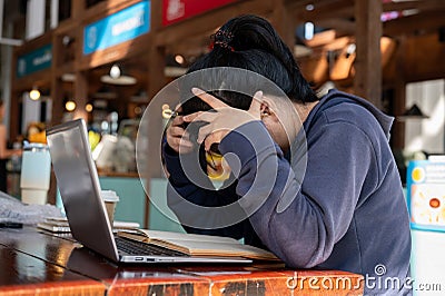 A stressed Asian woman is working on her project on her laptop, facing issues with her work Stock Photo