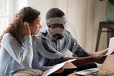 Stressed black couple with bills and laptop at home Stock Photo